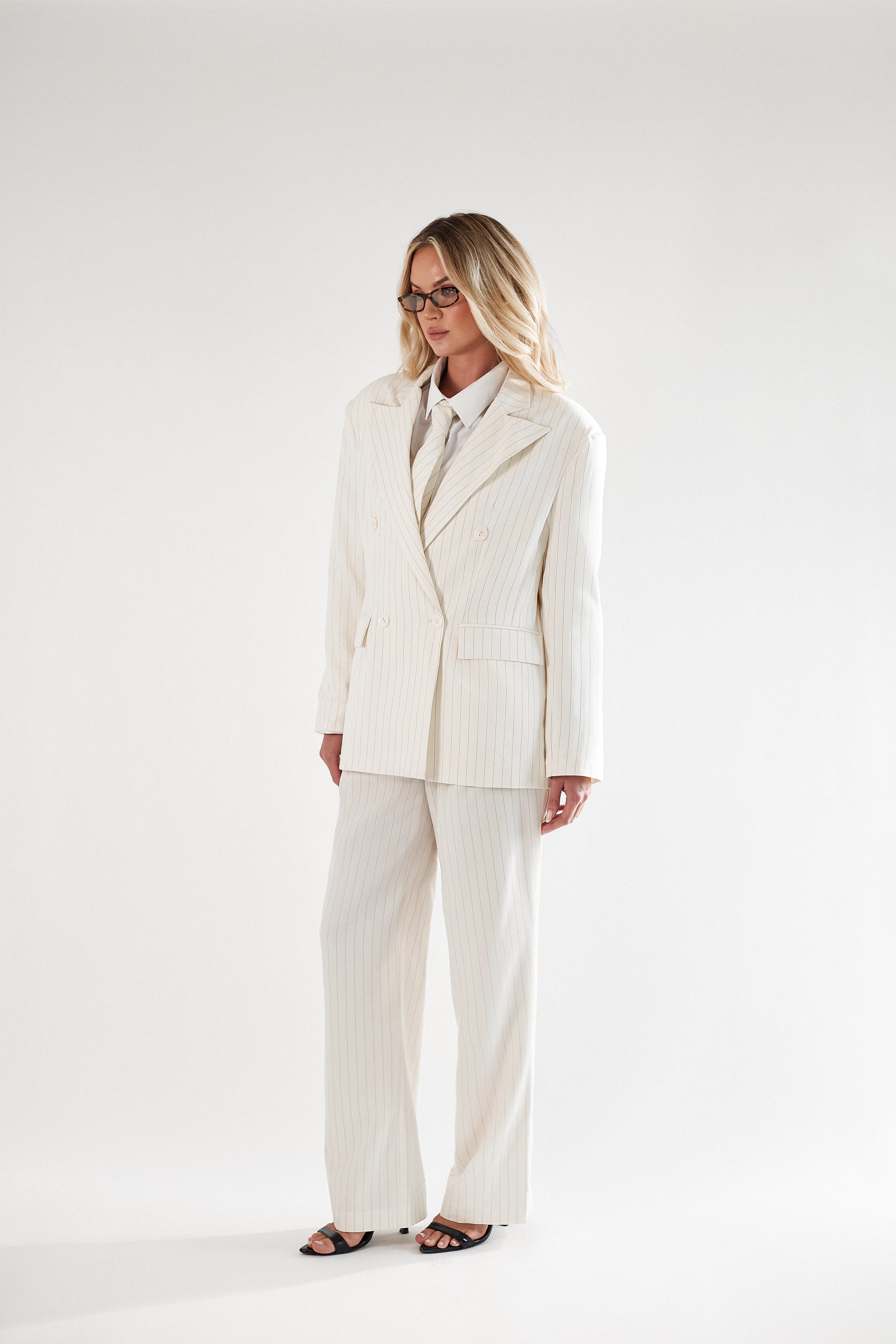 Kremowy garnitur damski w prążek z krawatem. Marynarka i spodnie