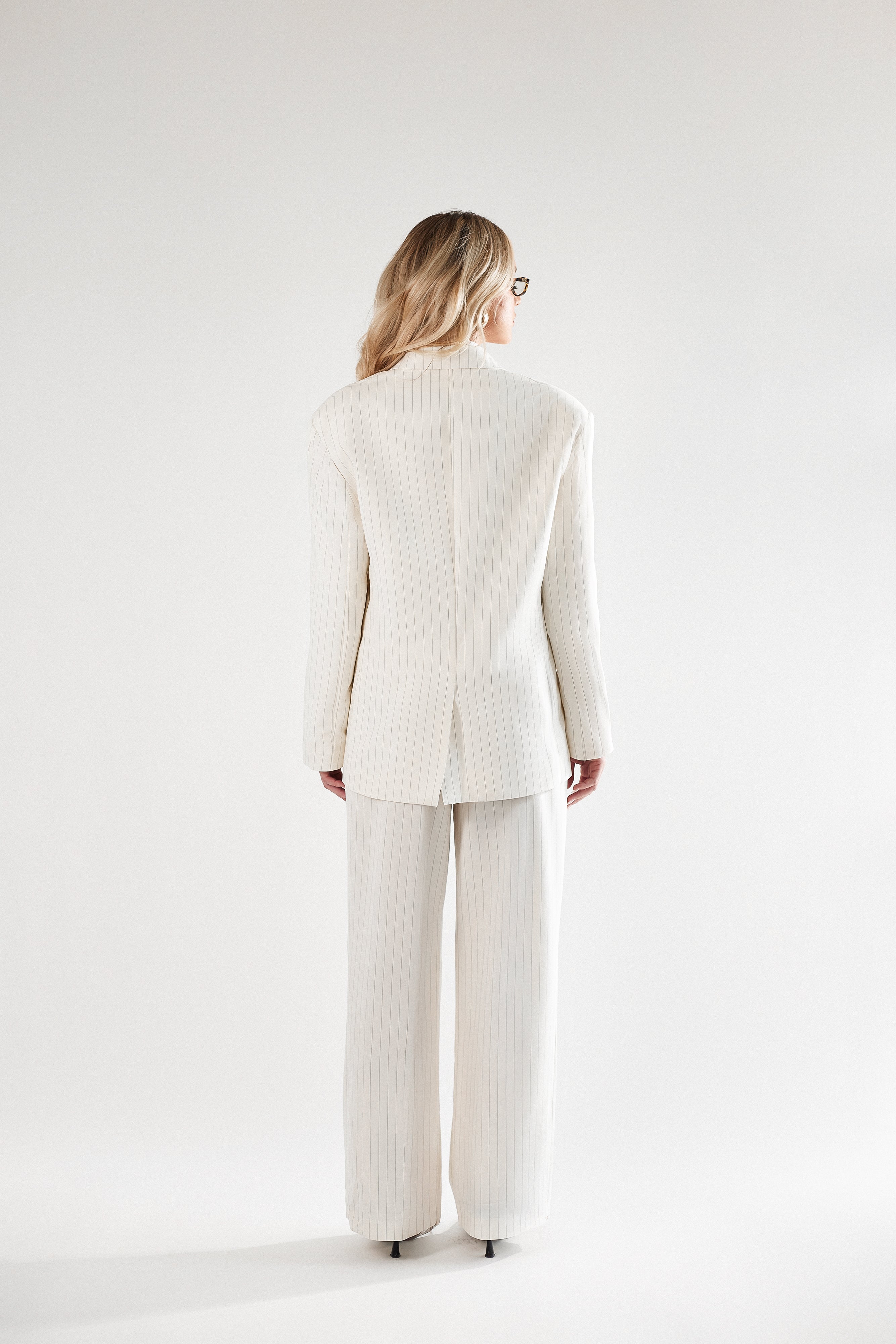 Kremowy garnitur damski w prążek z krawatem. Marynarka i spodnie
